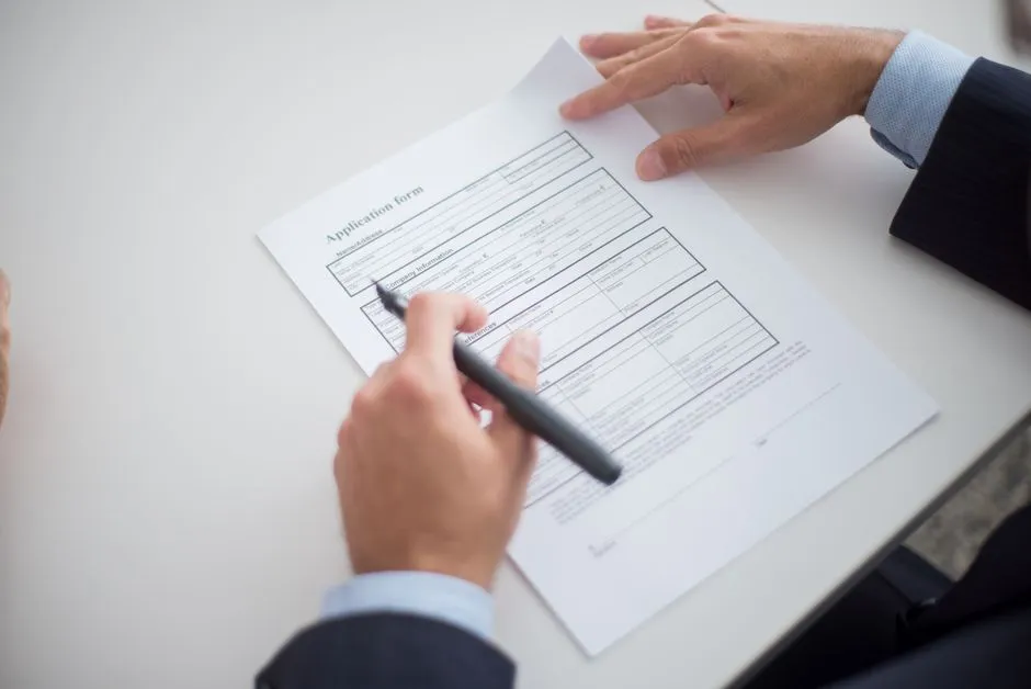 A person reviewing printed application paperwork, illustrative of gathering documents for a rental housing application.